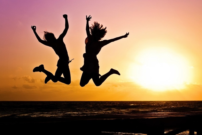 Twee mensen springen in de lucht bij zonsondergang